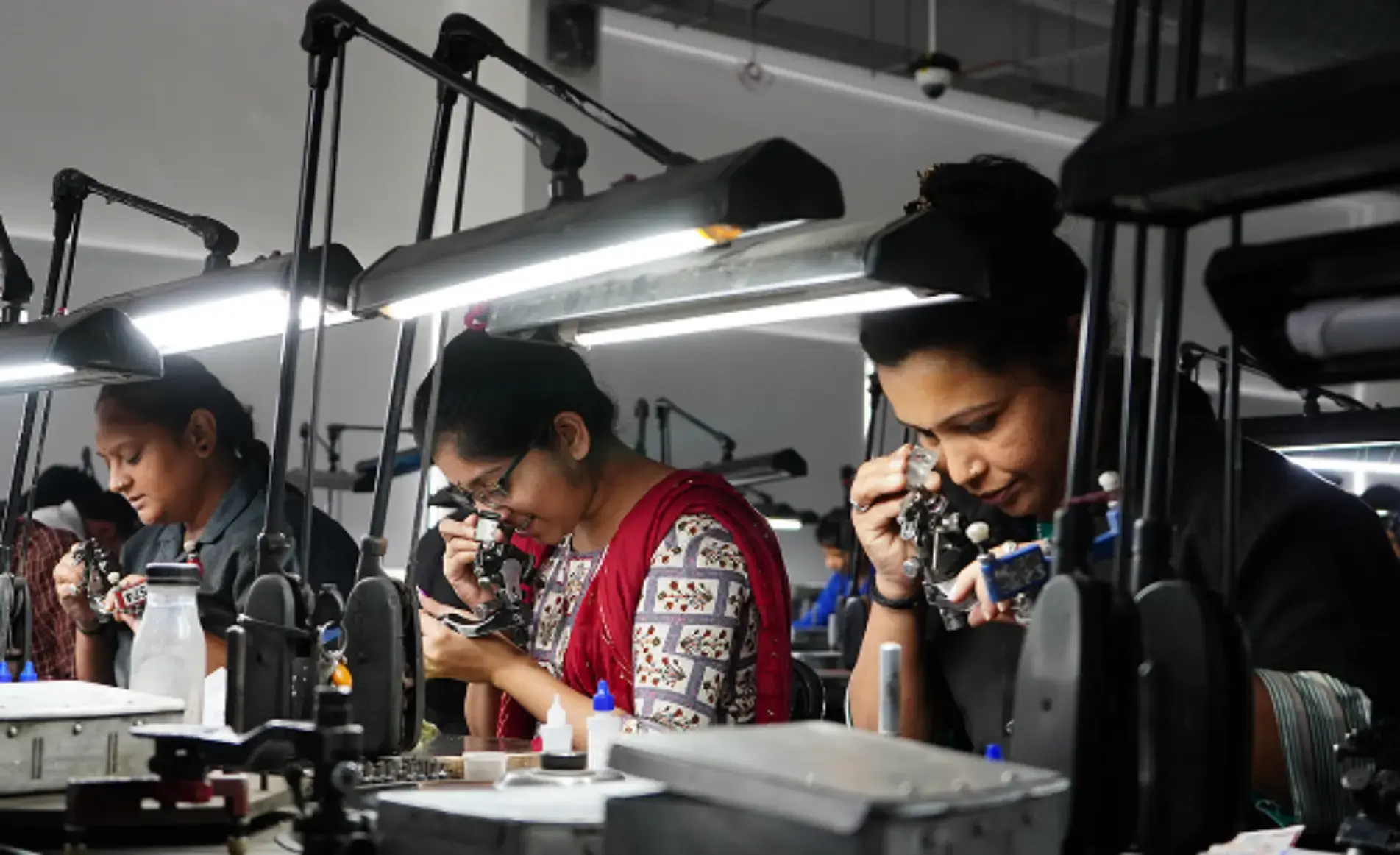 Artisans inspecting diamonds through loupes at their workstations