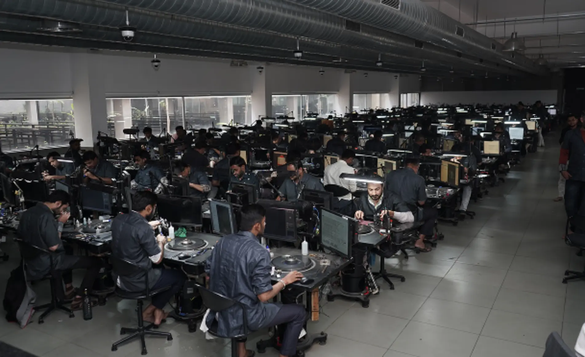 Rows of artisans working at diamond polishing benches on a manufacturing floor
